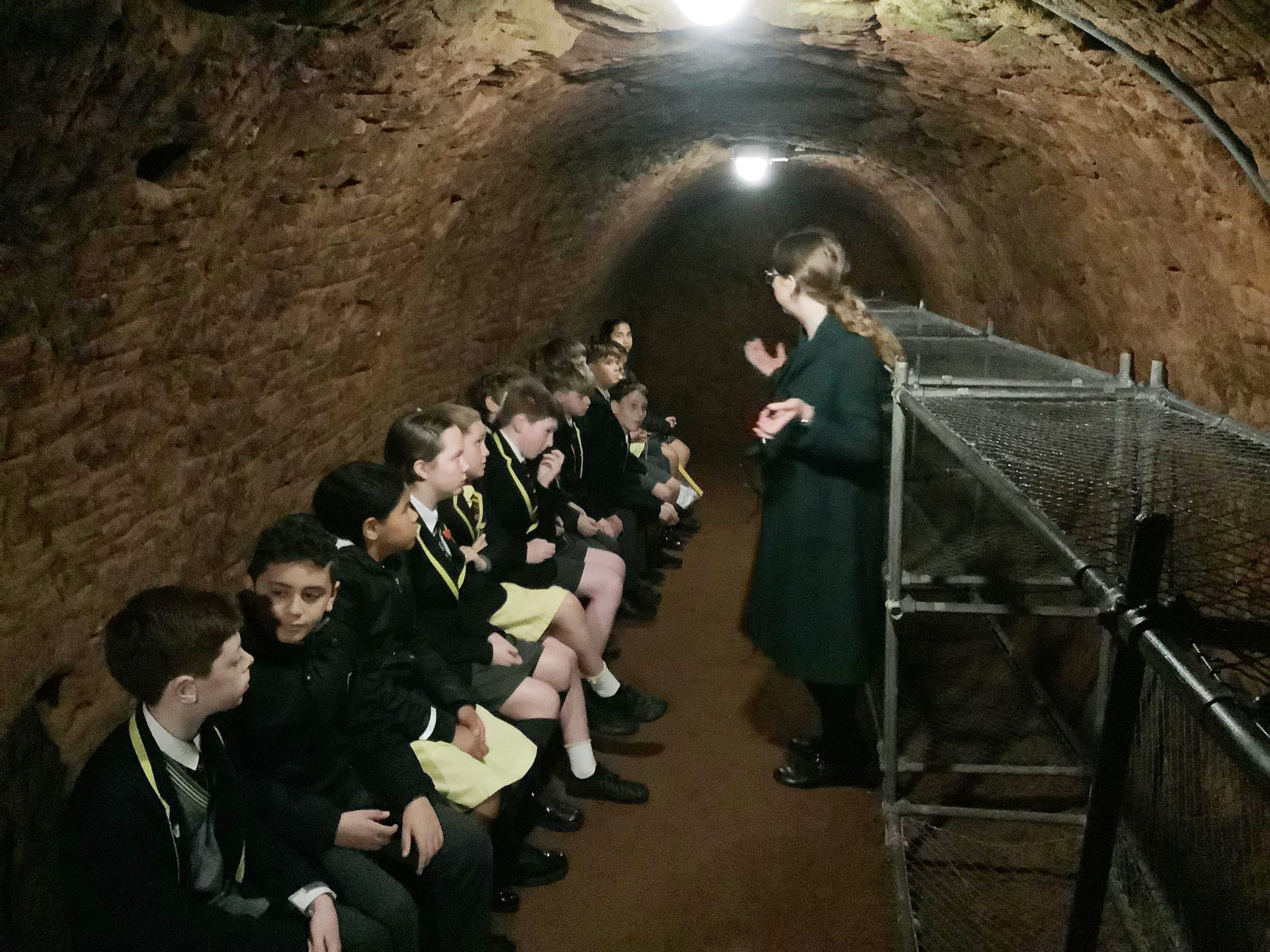 Junior School pupils sitting in a shelter during their visit to Stockport Air Raid Shelters