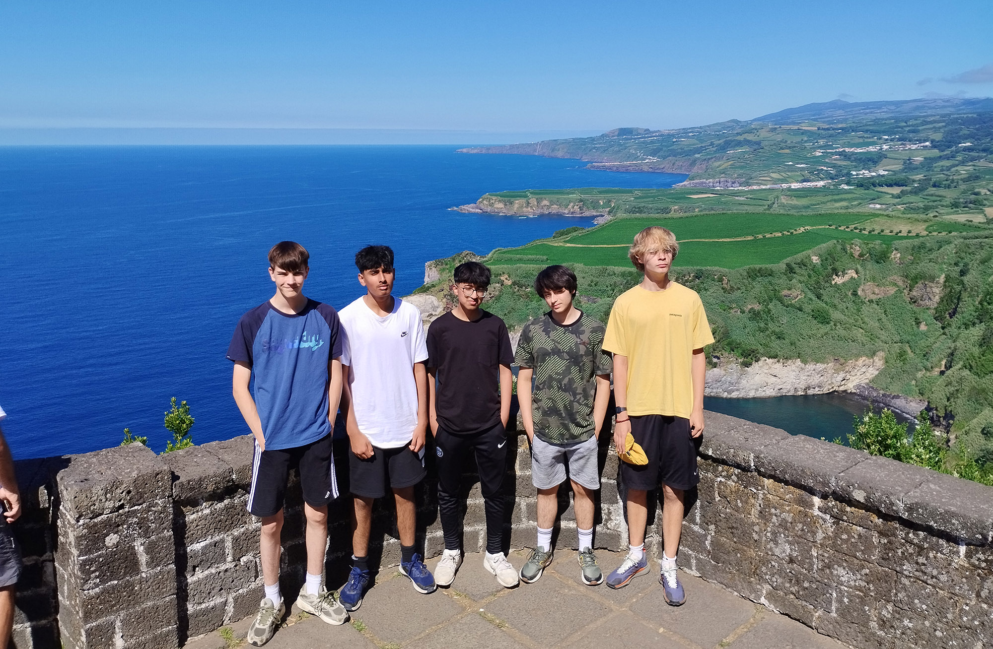 Students on the Geography trip to the Azores sit in front of a view of the sea