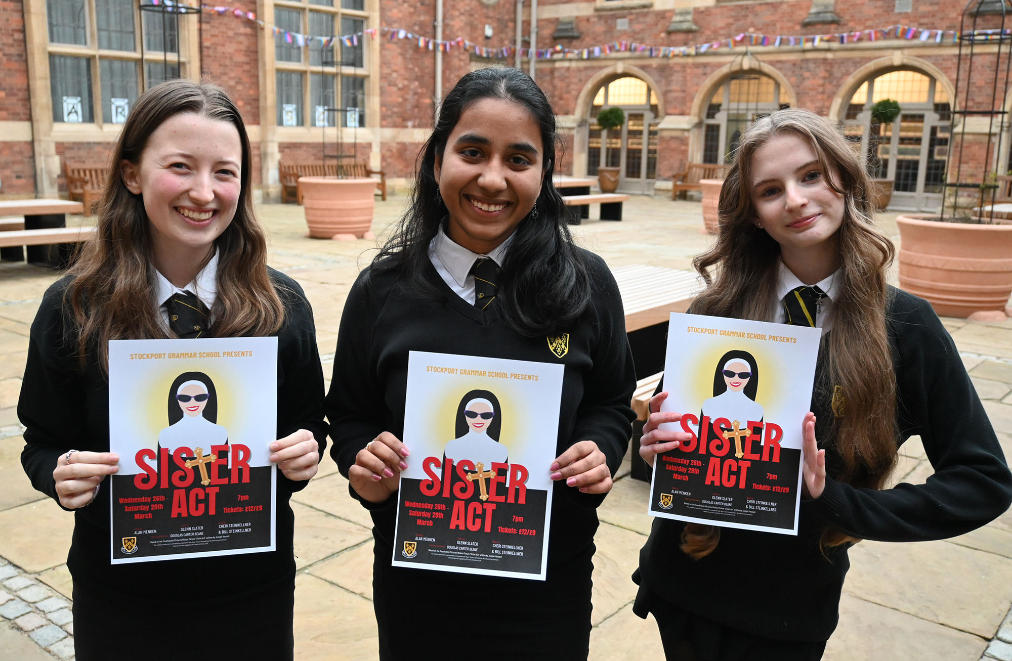 Actors taking part in the production of Sister Act posing for a photo with a poster of the show