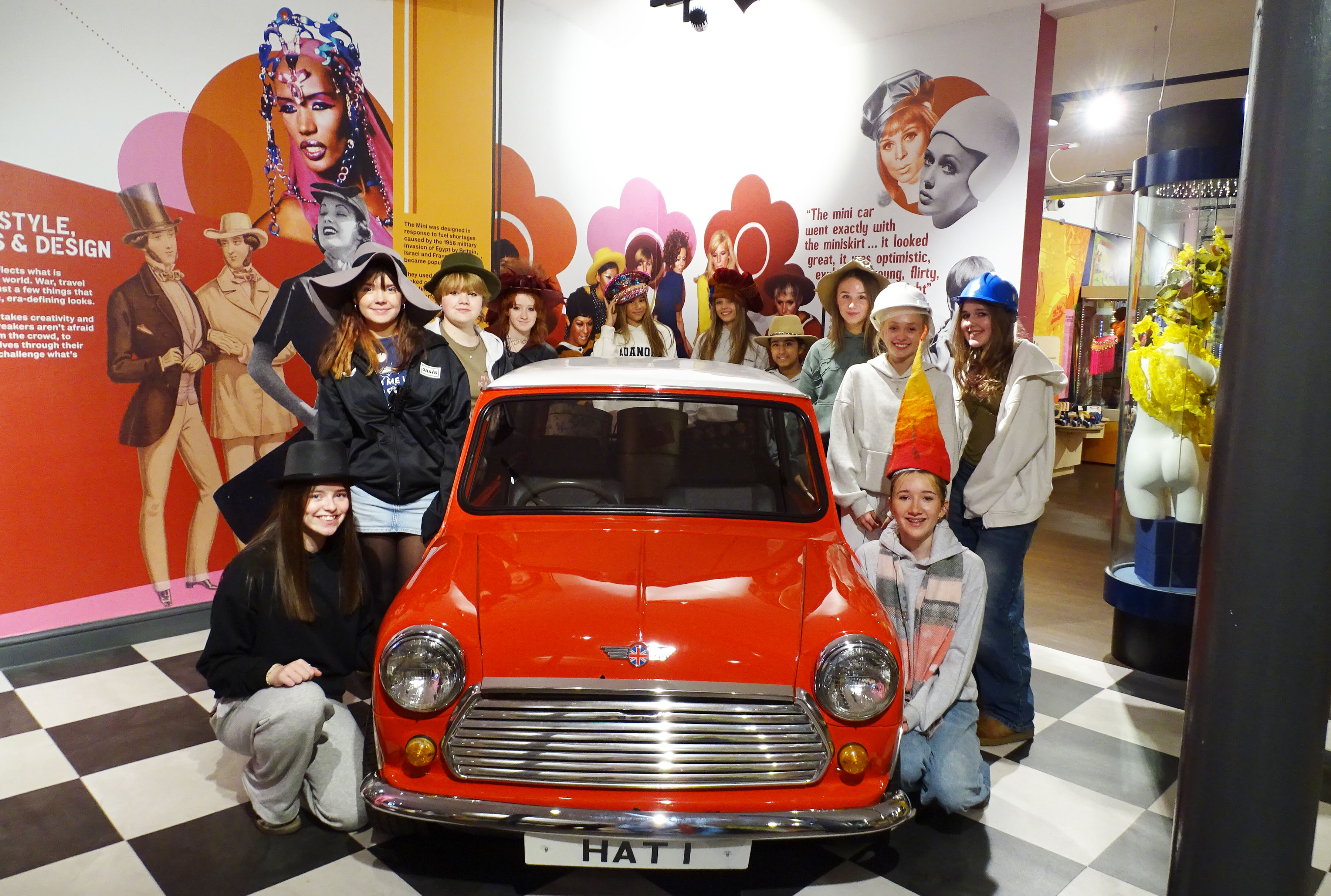 Fourth Year Textiles pupils pose for a photo around a car during a trip to the Hat Works Museum